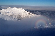 Tatry , zima, Kasprowy Wierch, widok na Giewont, widoczne Widmo Brockenu. Mamidlo gorskie, zjawisko Brockenu - rzadkie zjawisko optyczne spotykane w gorach, polegajace na odbiciu powiekszonego cienia obserwatora, niekiedy z teczowa obwodka (gloria), na chmurze. Nisko polozona chmura pelni role ekranu, jesli obserwator znajdzie sie miedzy nia a sloncem. Nazwa zjawiska podchodzi od szczytu Brocken w gorach Harz, gdzie po raz pierwszy zostalo zaobserwowane.